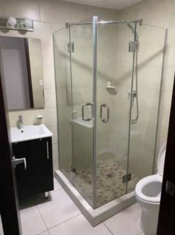 Contemporary bathroom with tiled walls, glass shower, vanity, and toilet PH Luxor Towers Obarrio Panama