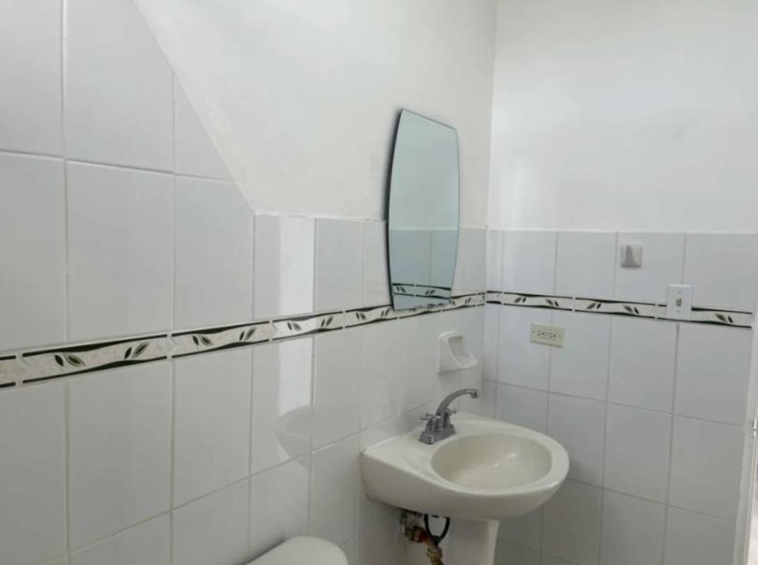 Simple bathroom with mirror, sink, and decorative tiles PH Parque Lefevre Panama