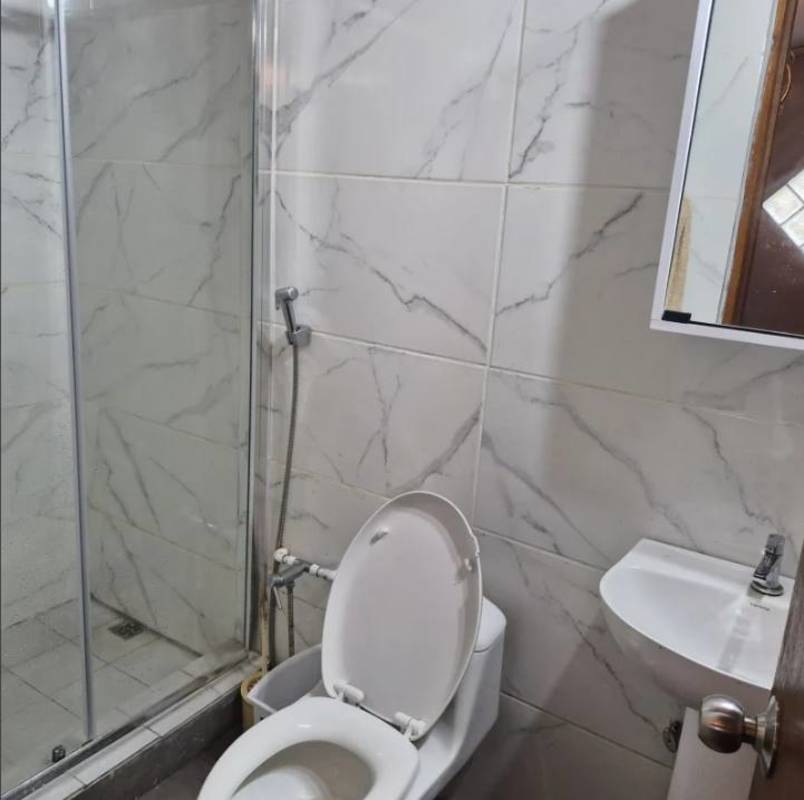 Bathroom with glass shower enclosure, marble-style tiles, pedestal sink in mountain home Cerro Azul Panama