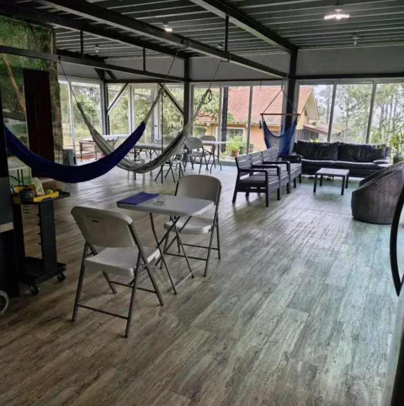 Lounge with hammocks, folding chairs, large windows overlooking greenery in mountain residence Panama