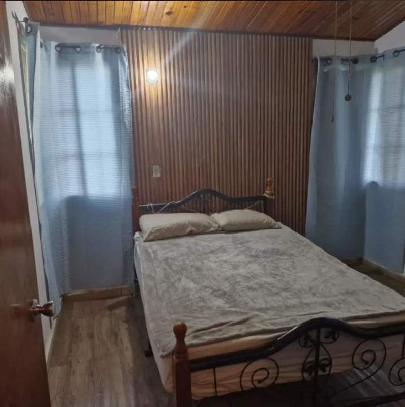 Rustic loft bedroom with wood flooring, angled ceiling, wooden railings and AC in mountain home Panama
