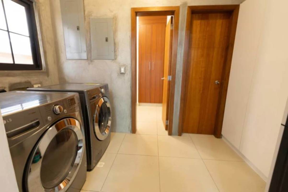 Kitchen with granite countertops, wood cabinets, view into laundry area Costa Sur Panama