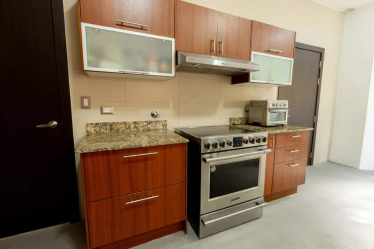 Kitchen with wood cabinetry, granite, stainless range Costa Sur Panama home