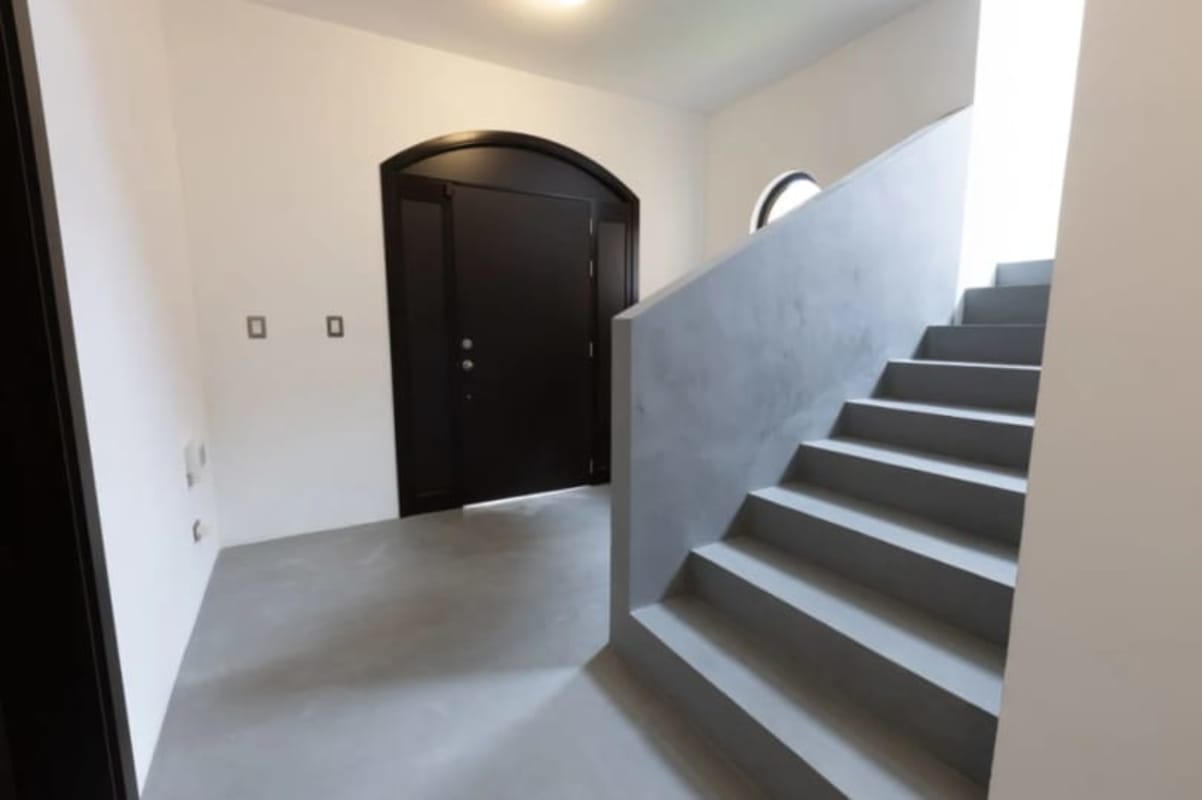 Minimalist entry hall with black door and floating concrete stairs in Costa Sur Panama