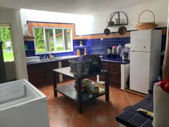 Bright living area with wicker furniture open to rustic kitchen island in Coronado beach house Panama
