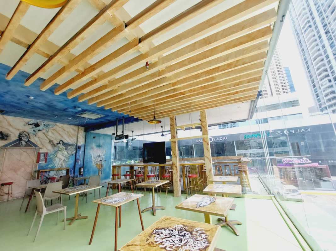 Colorful dining space with open ceiling, pendant lights, mural at Boutique Balboa Panama City