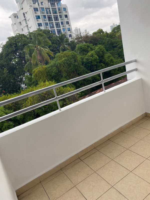 Modern balcony with terra cotta tiles, metal railing overlooking trees at PH Carrasquilla Urban Center