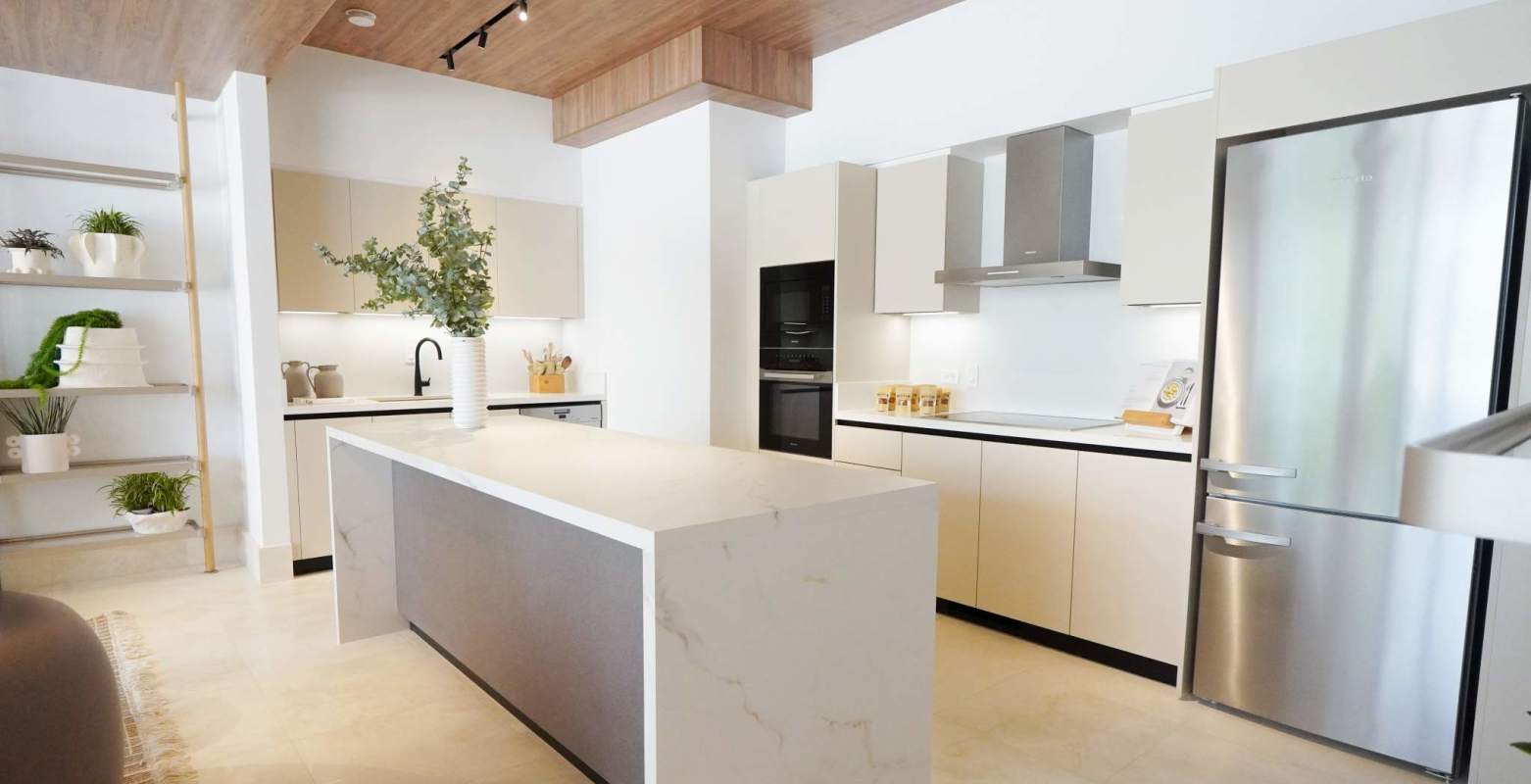 Open modern kitchen with marble island, beige cabinets in Oceana Santa María Panama