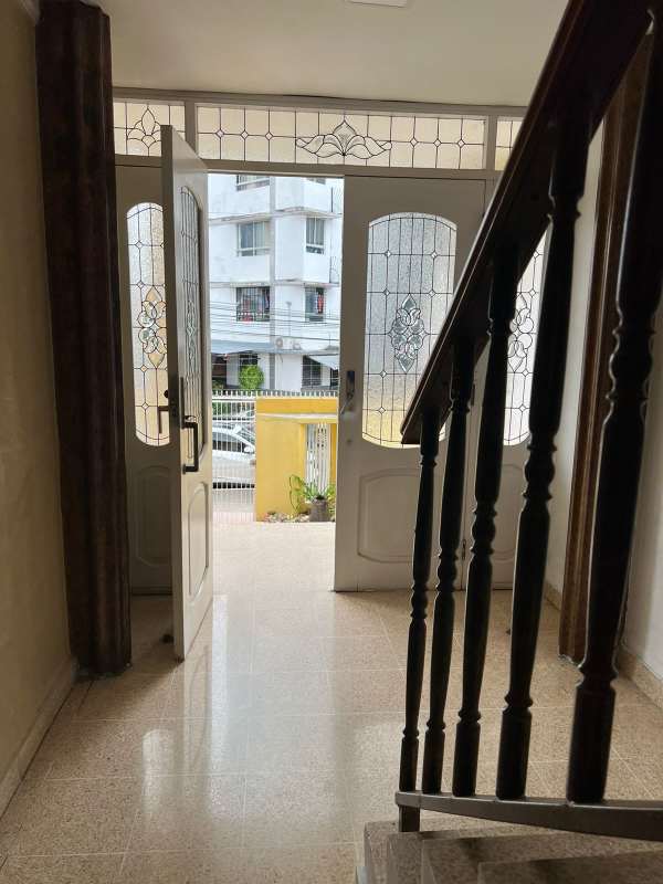 Bright entrance hallway with glass front door, stairway, traditional details in house on 12 de Octubre Panama City