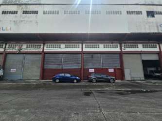 Industrial warehouse exterior view with multiple loading docks and truck access at Cocosolito