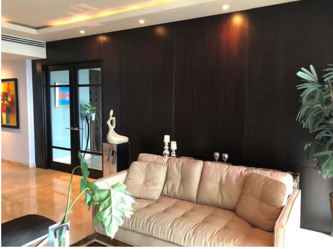 Modern living area with beige sofas, marble floors, accent wall, and ocean views in PH Torre Zeus Costa del Este