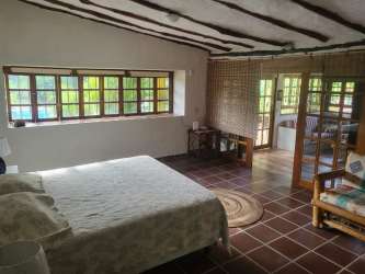 Rustic bedroom with exposed wooden beams, large windows, natural decor in Coronado Panama beachhouse