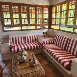 Sunroom with built-in striped sofas, wood accents, large windows at Coronado beach rental