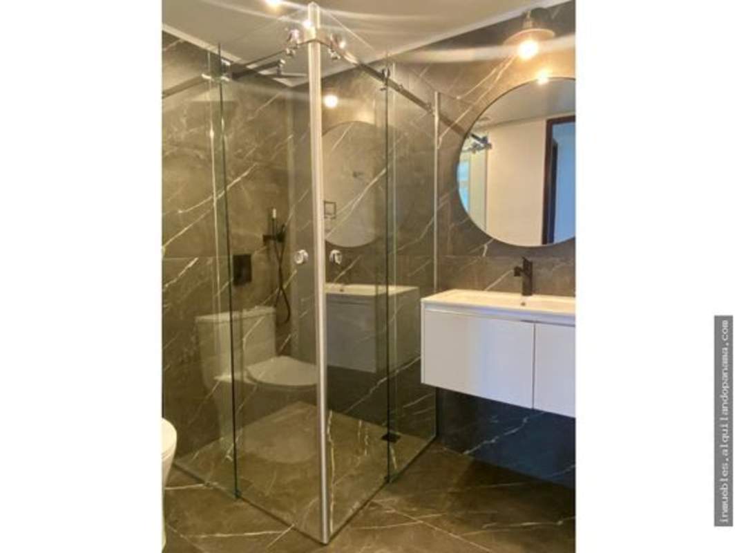 Modern bathroom with glass shower, floating vanity, marble tiles at PH Pacific Village Panama City