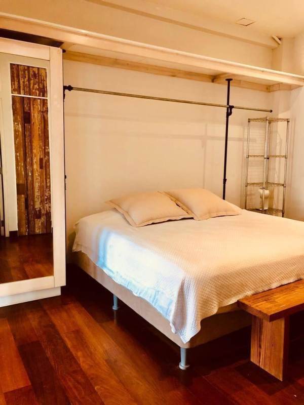 Minimalist bedroom with open closet design and hardwood floors in Casco Viejo historic apartment