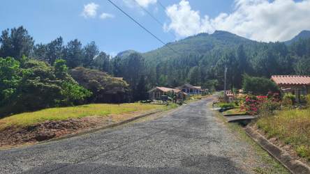 Paved community road with houses and mountain backdrop Altos del María Panama