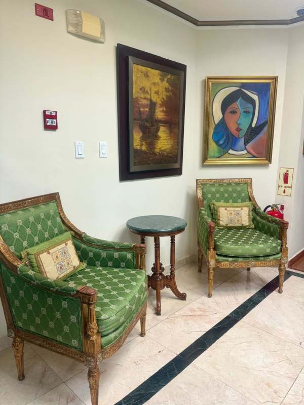 Waiting area with green armchairs, round marble table, wall paintings in BICSA Tower Panama