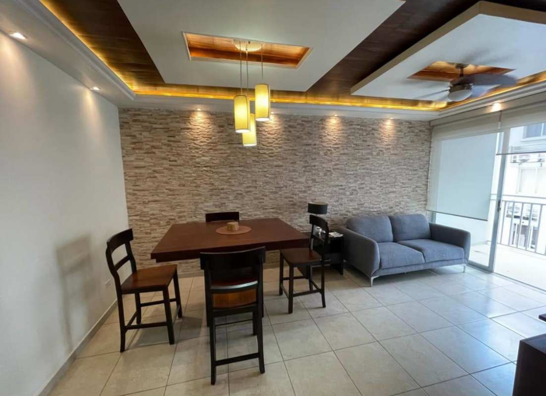 Modern dining and living space with stone accent wall, pendant lights and balcony doors in furnished rental