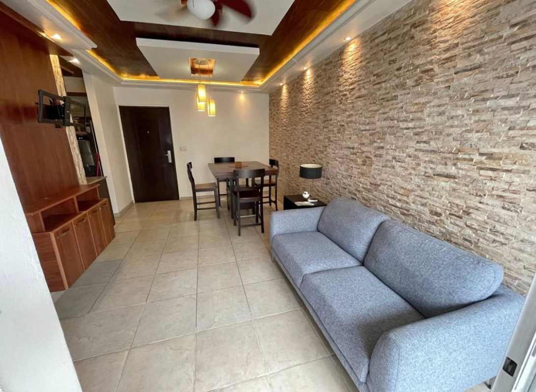 Living dining space with stone accent wall, tray ceiling, ceiling fan in furnished Panama apartment