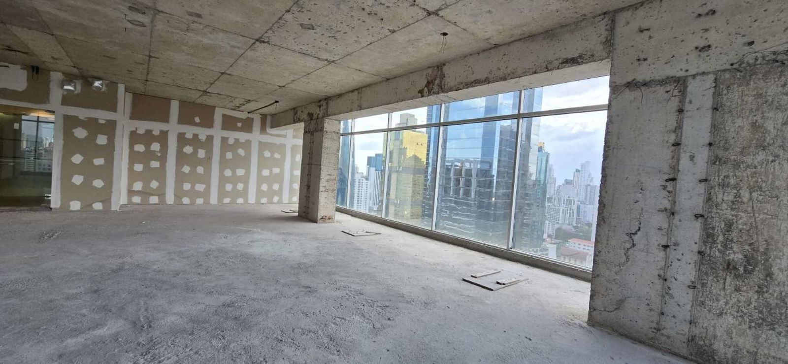 Unfinished office space with exposed concrete ceiling and floor-to-ceiling windows in PH Sortis Obarrio Panama City