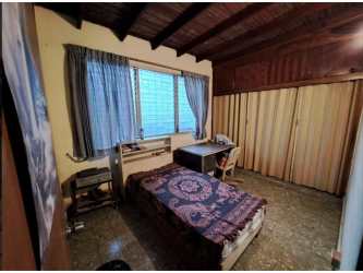 Bedroom with exposed beams, window light and basic furniture in Carrasquilla Panama for sale