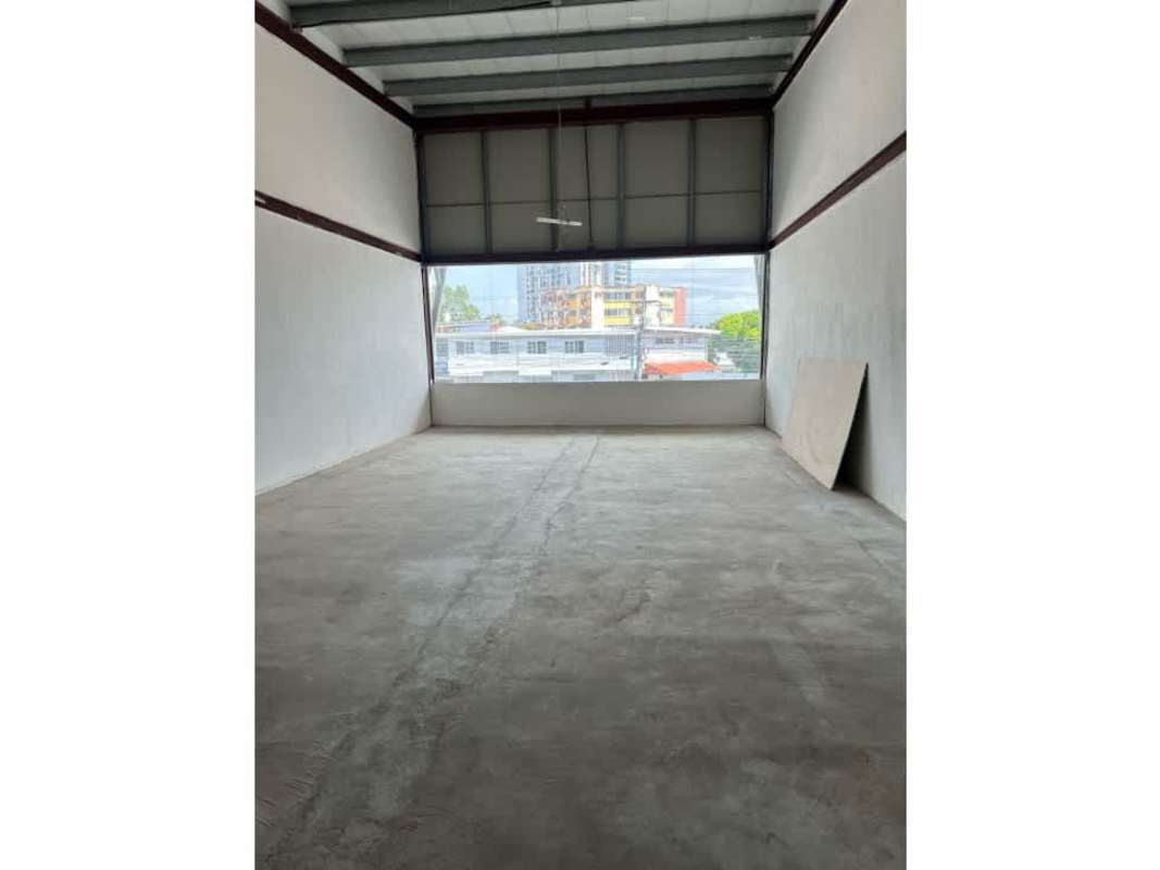 Commercial area street with vehicles, parking lot, city skyline background under cloudy sky