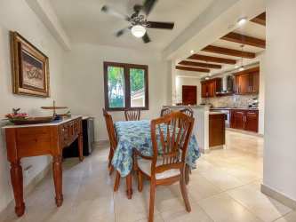 Dining room with view to garden and kitchen inside lakefront villa at Buenaventura Panama