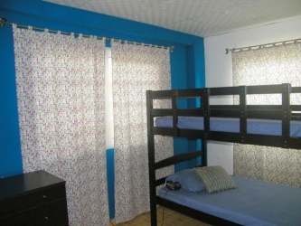 Secondary bedroom with bunk beds blue accent wall green view Barrio Colón country house Panama