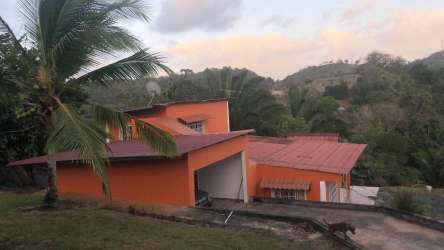 Orange two-story house with metal roofing tropical plants hillside lot Barrio Colón Panama