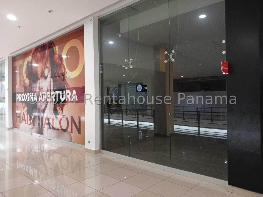 Empty commercial retail space with wood flooring and brand walls inside mall