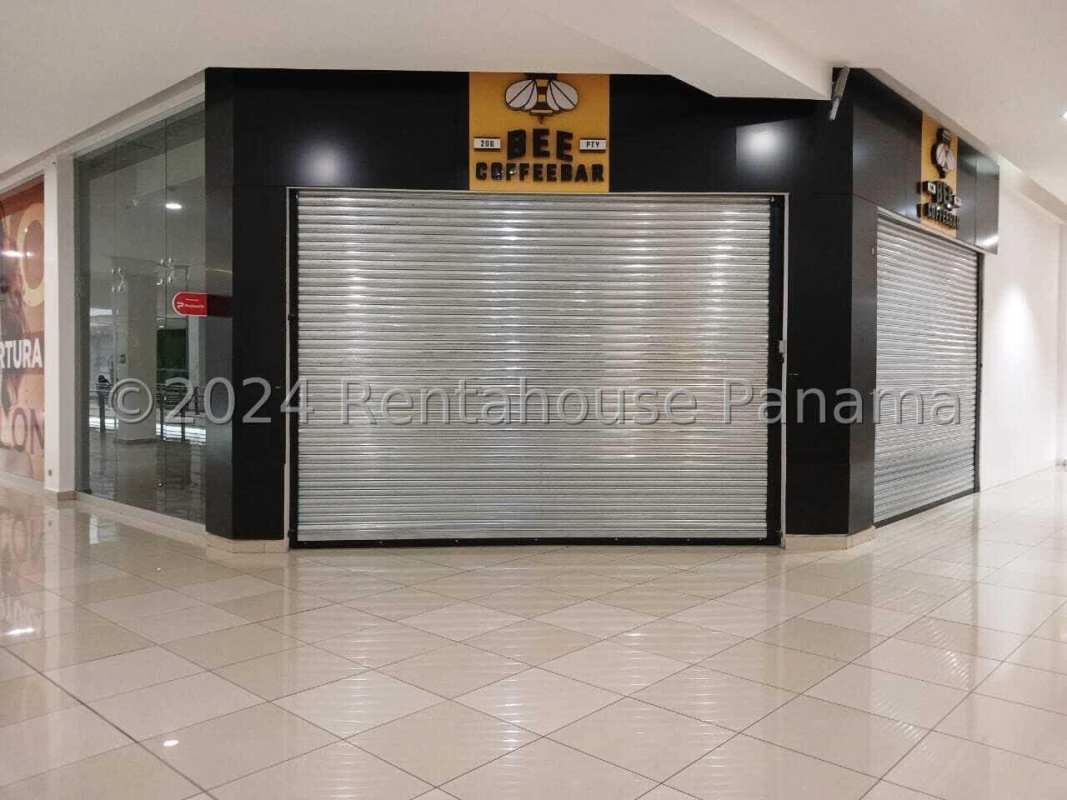 Commercial mall storefront with glass walls and metal shutters for security