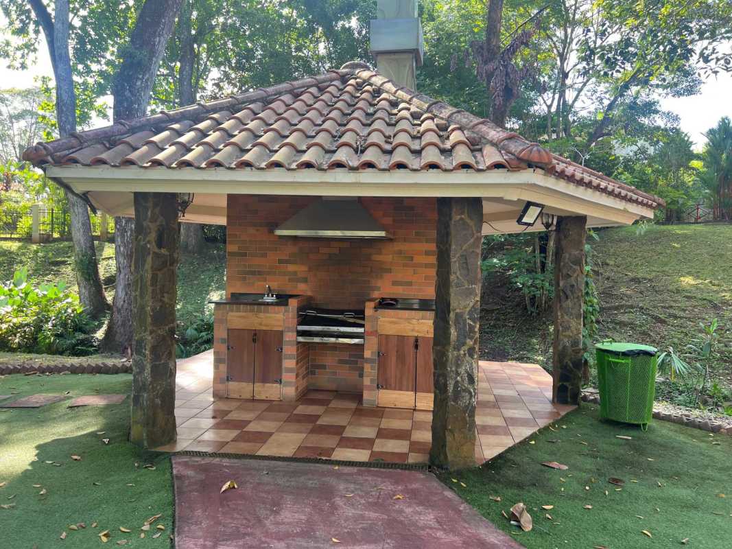 Covered outdoor kitchen with brick BBQ grill and tiled roof surrounded by garden Clayton Panama