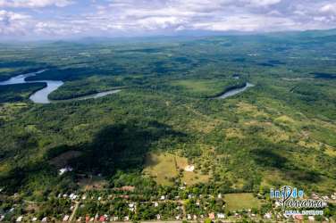 Aerial panorama of green pasture, mountain backdrop and river on 55 hectare ranch Las Lajas Chiriquí