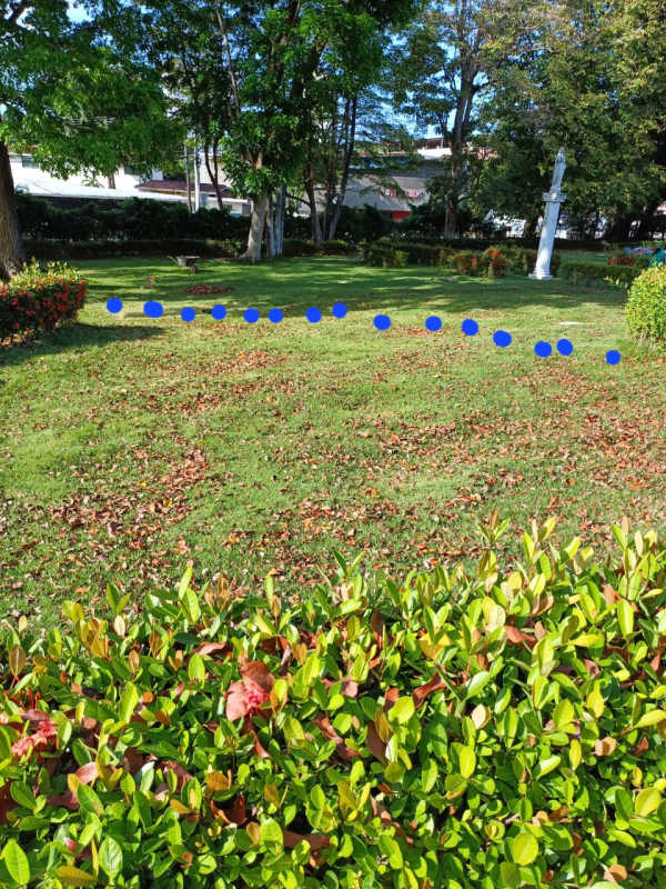Green lawn with white garden sculpture and bench at Jardín de Paz cemetery Panama City