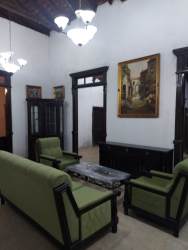 Bright traditional living area with ceiling beams and green furniture in La Villa Panama