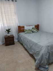 Simple cozy bedroom with gray bedding and natural light in colonial home Panama