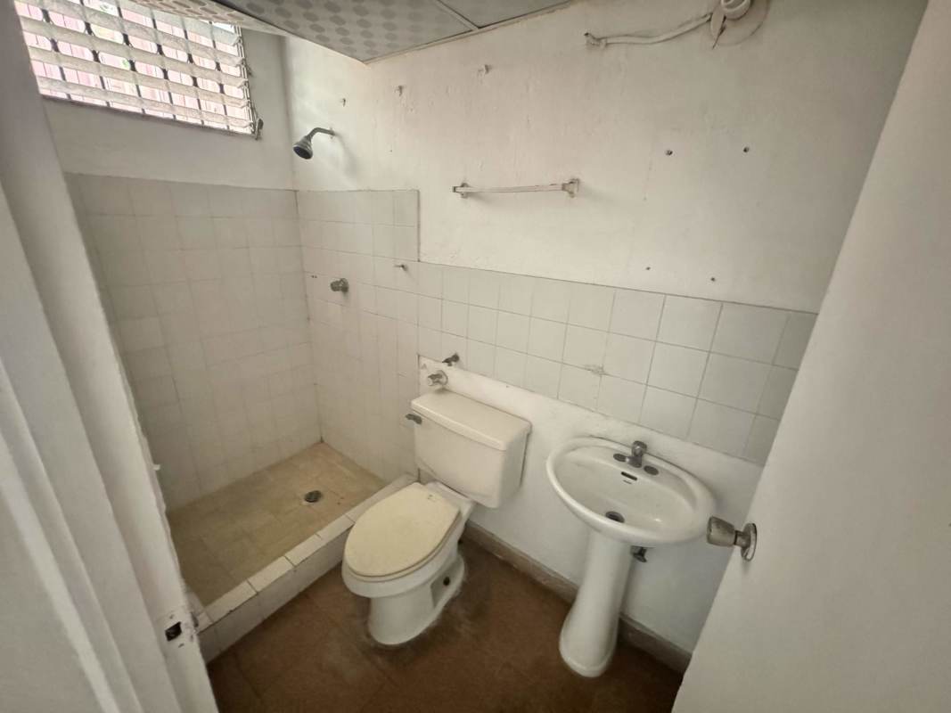 Compact bathroom with pedestal sink, walk-in shower, barred window in apartment Rio Abajo