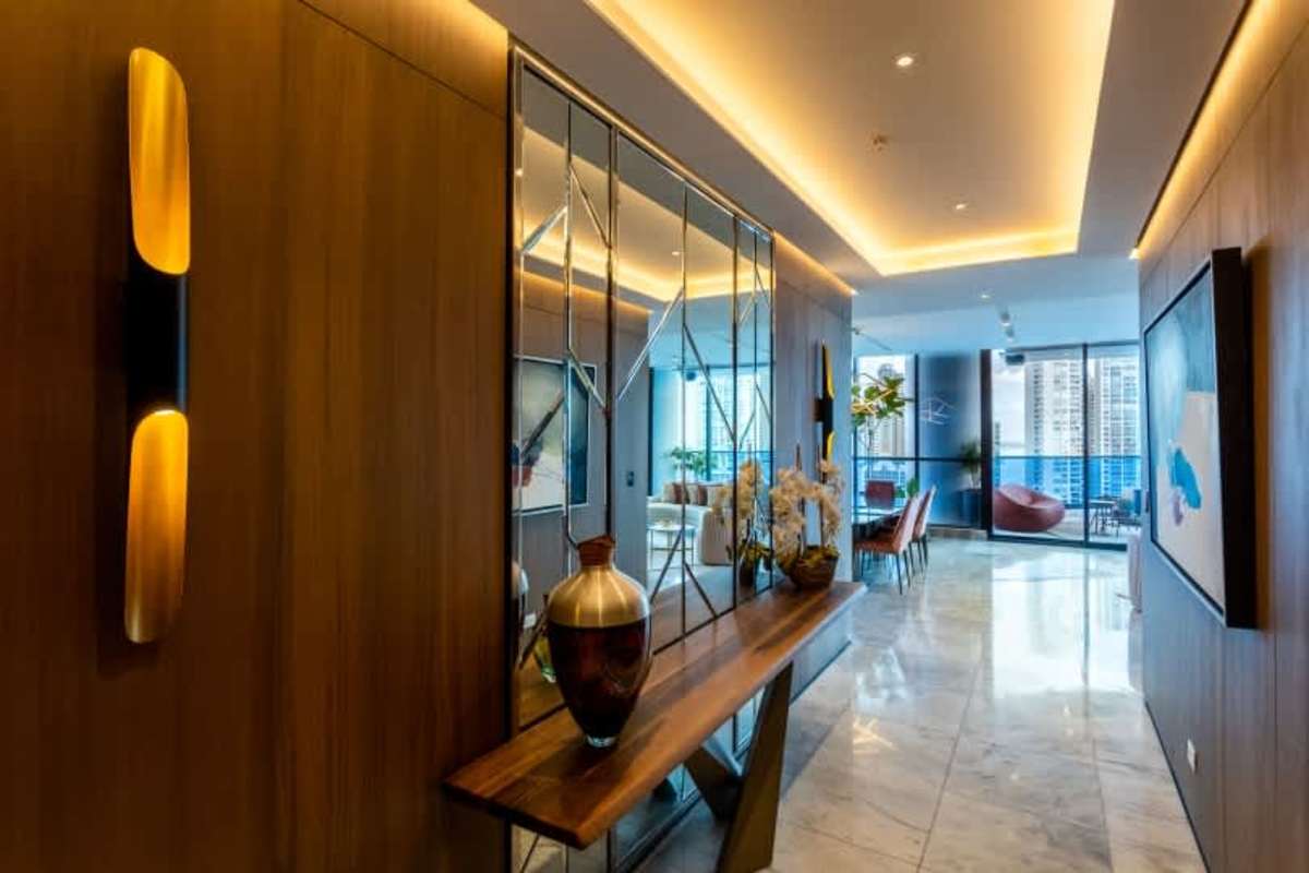 Modern apartment hallway with wood panels, marble floors, city skyline behind floor-to-ceiling windows at PH Punta Paitilla Sky Tower