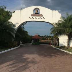 Spanish colonial style arched entrance gate white stucco and bell Coronado Equestrian Club Panama