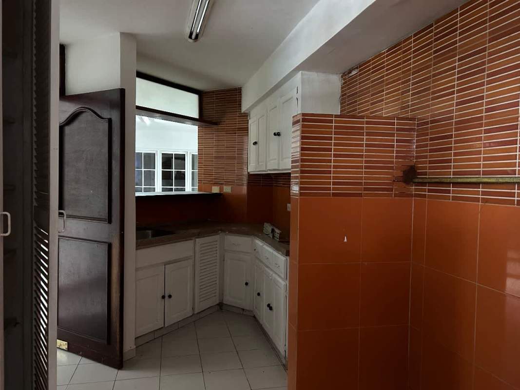 Kitchen space with white cabinetry, brown tile backsplash, and L-shaped counters in duplex Obarrio Bella Vista