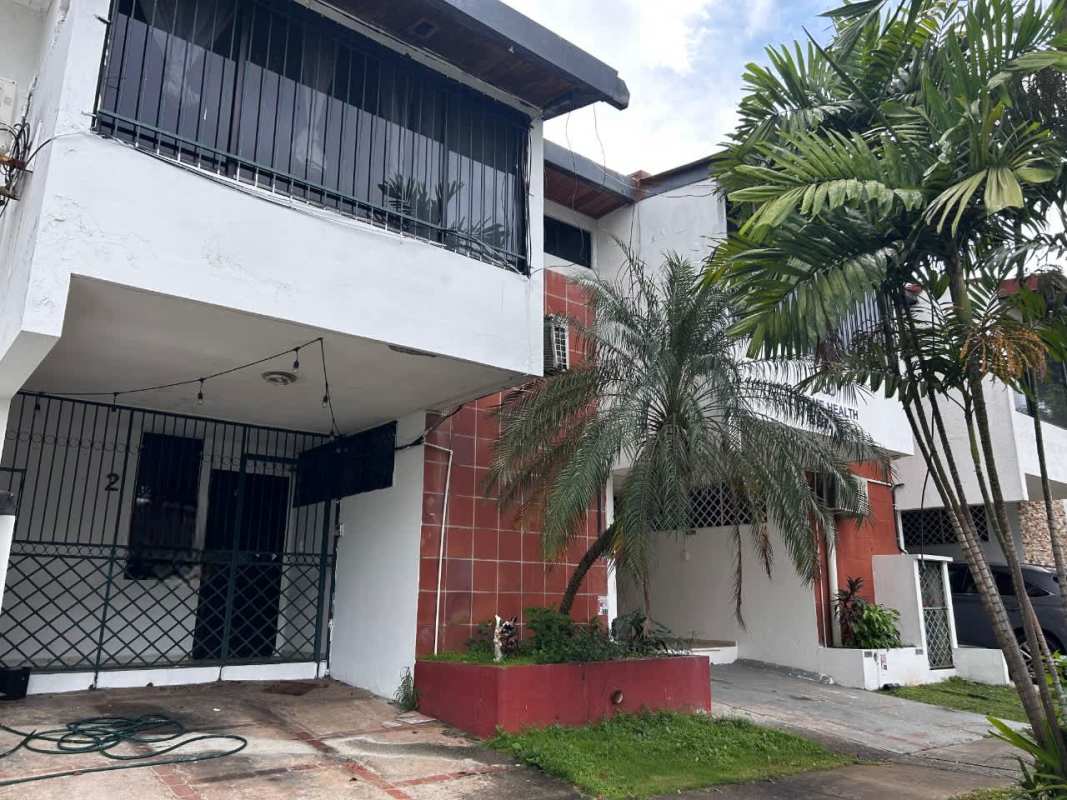 Exterior view of duplex with driveway and small landscaped yard in Panama City