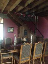Rustic dining area with wooden beams, iron chandelier and large table at Sora Panama estate