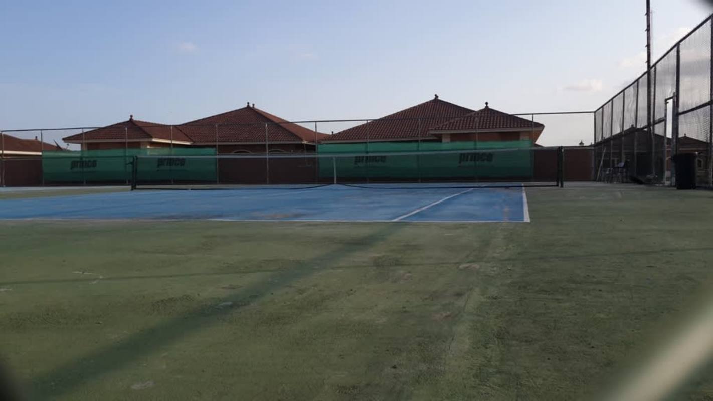 Outdoor tennis court with fencing and residential homes at Sunset Coast Costa Sur community Panama City