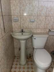 Exterior of simple single-story apartment with barred windows and covered pathway in La Chorrera