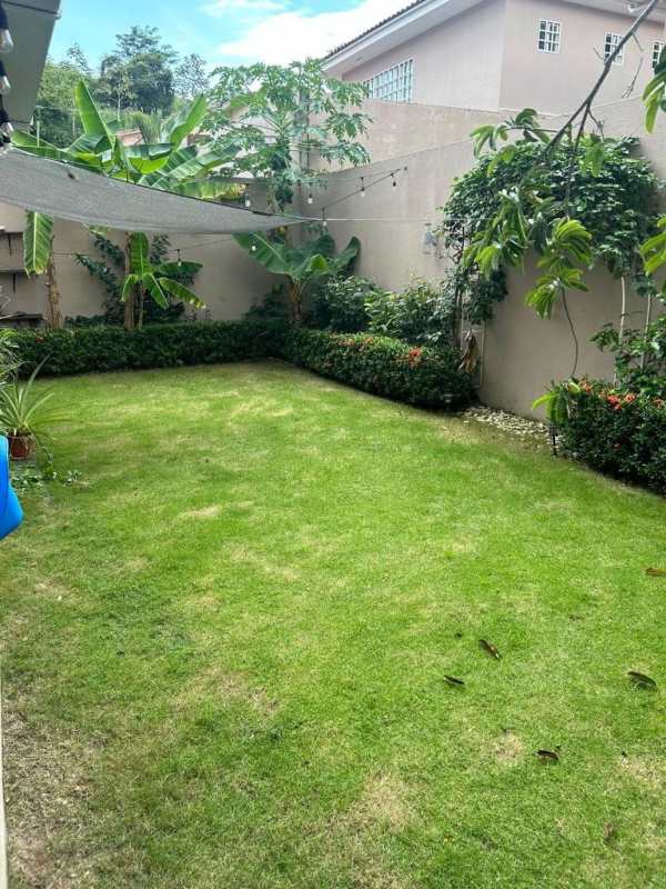 Fenced private backyard garden with grass, tropical plants, banana trees and privacy wall at Villa Tiber Brisas del Golf Panama
