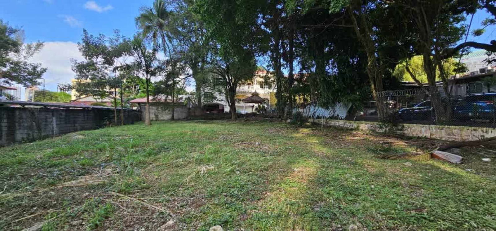 Empty fenced green lot surrounded by residential towers near Multiplaza Punta Pacifica in Panama City