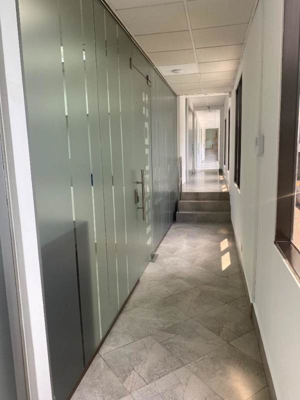 Modern office corridor with frosted glass walls and tiled flooring Business Center Panama City