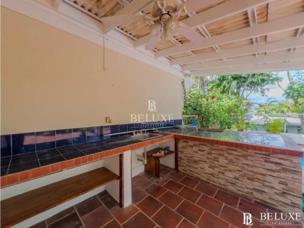 Covered patio with outdoor kitchen bar ceiling fans next to pool garden Clayton rental Panama