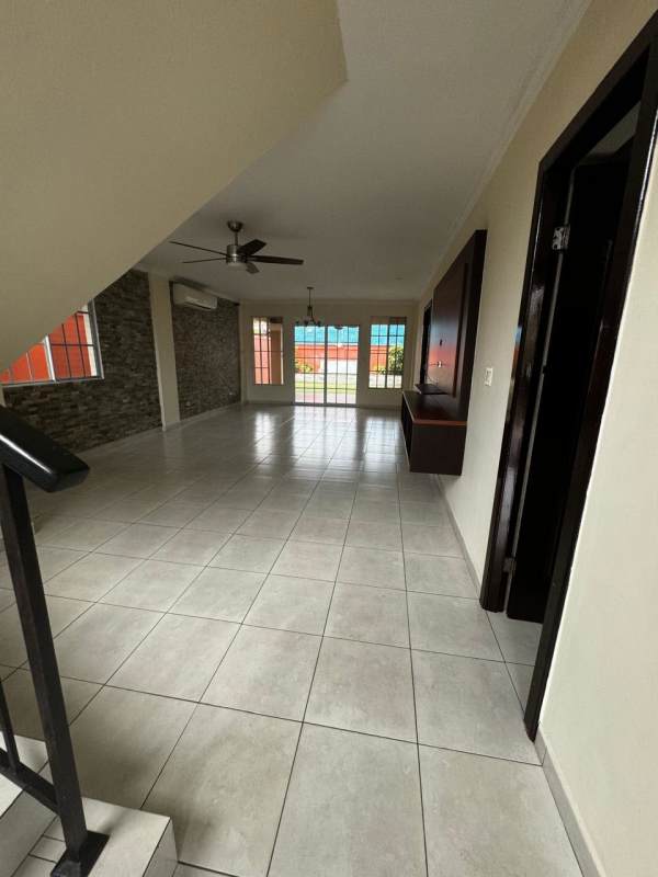 Large living room with stone accent wall, windows, and tile floor in Castel Novo house Panama