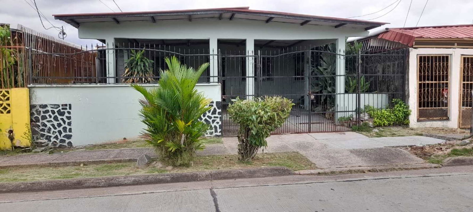 Exterior front facade of one-story house with gated yard and porch in Don Bosco Panama City